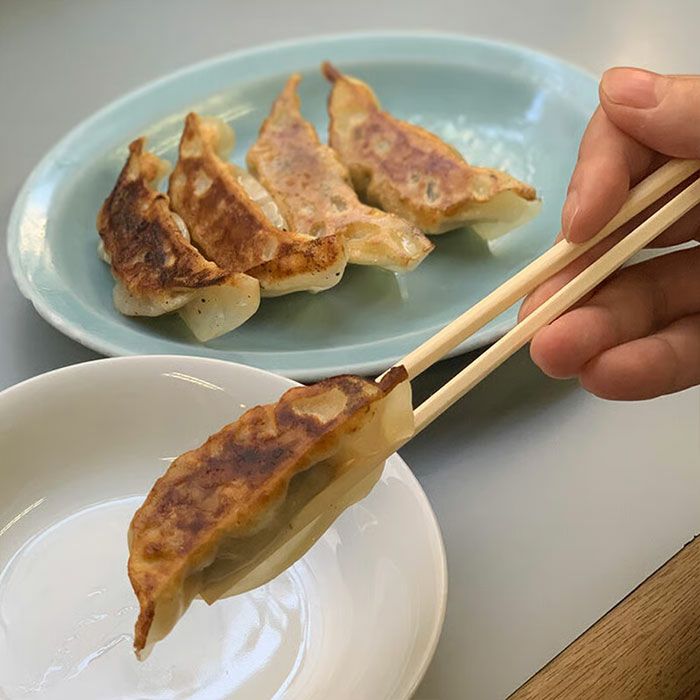 箸で持ち上げた餃子。薄皮から透けるジューシーな質感